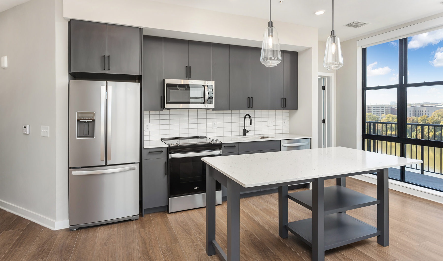 A new standard of living Model kitchen at Oxbow apartments for rent in Nashville, TN, featuring wood grain floor paneling and a kitchen island.